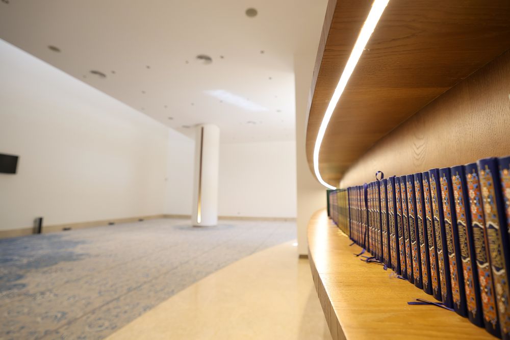 Prayer hall with lit oak Qur’an shelf